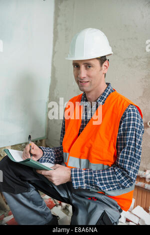 Germany, Munich, Portrait of construction worker taking notes Stock Photo