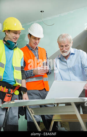 Architect and two construction workers at construction site of new building Stock Photo