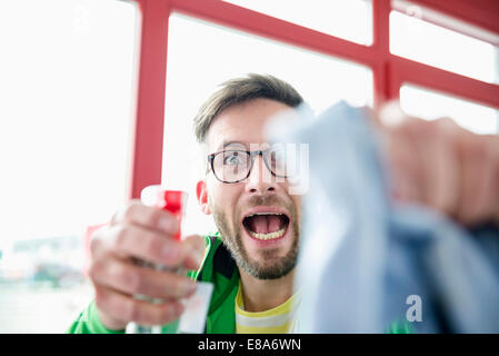 Young man holding cleaning liquid bottle and cloth Stock Photo