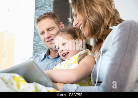 Parents with daughter sitting on couch using tablet PC Stock Photo