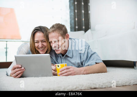 Couple lying on floor with digital tablet Stock Photo