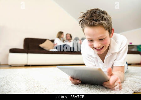 Happy boy in living room using digital tablet with parents in background Stock Photo