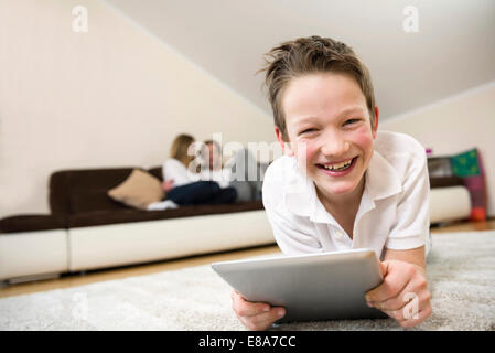 Happy boy in living room using digital tablet with parents in background Stock Photo