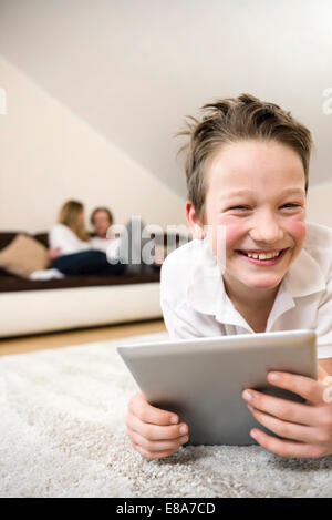 Happy boy in living room using digital tablet with parents in background Stock Photo