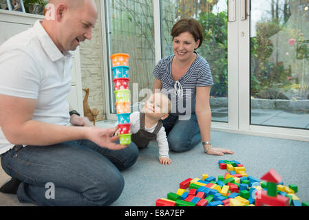 Parents and little son sitting on ground of living room playing together Stock Photo