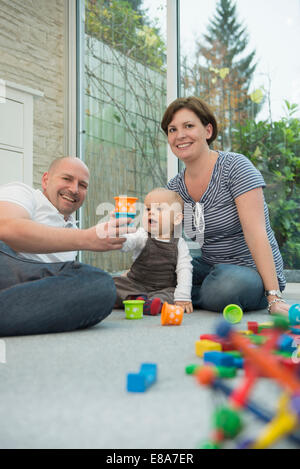 Parents and little son sitting on ground of living room Stock Photo