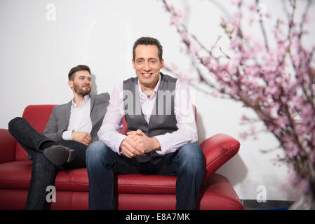 Two young men sitting on sofa waiting Stock Photo