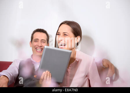Young couple holding tablet computer laughing Stock Photo