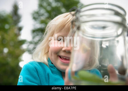 Small blonde girl collecting snails in jam-jar Stock Photo