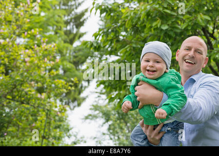 Father holding baby boy in arms playing flying Stock Photo