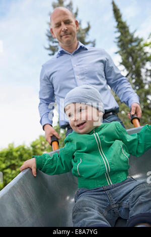 Father pushing baby son in wheelbarrow Stock Photo