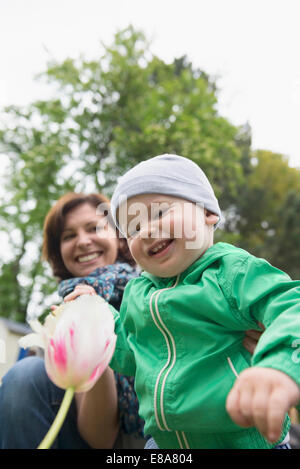 Mother and baby son looking at Tulip in garden Stock Photo