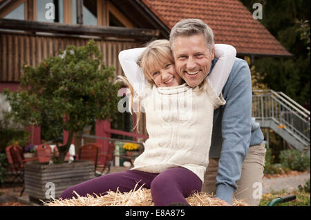 Daughter in wheelbarrow hugging father Stock Photo