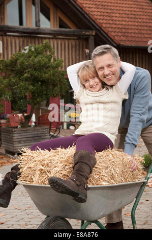 Smiling daughter sitting in wheelbarrow with mother and sisters ...