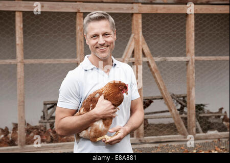 Farmer holding chicken on organic farm Stock Photo