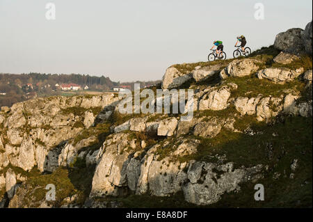 Young men mountainbiking at sunrise, Bavaria, Germany Stock Photo