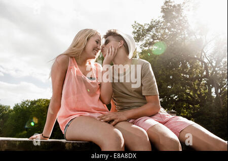 Teenage couple in love sitting on a jetty at lake Stock Photo