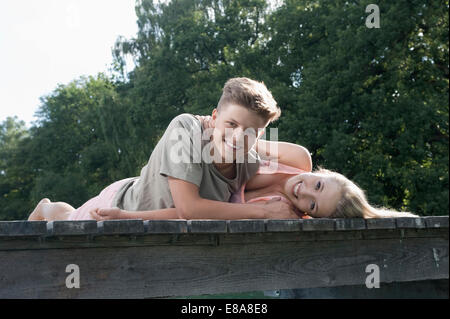 Teenage couple lying on a jetty at lake Stock Photo