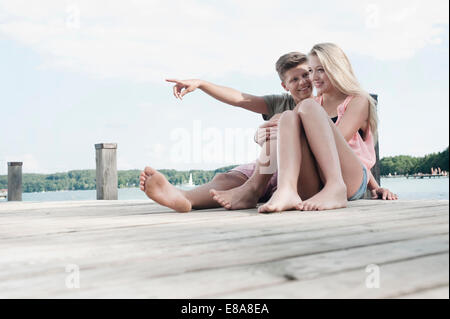 Teenage couple sitting on a jetty at lake Stock Photo