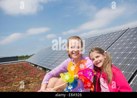 Two girls sitting next to photovoltaic panel Stock Photo