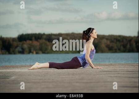 Woman practicing yoga on jetty, Woerthsee, Bavaria, Germany Stock Photo
