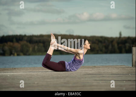 Woman practicing yoga on jetty, Woerthsee, Bavaria, Germany Stock Photo