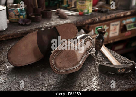 Pair of leather shoes, awl and hammer in a cobbler's shop Stock Photo
