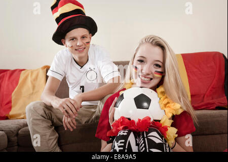 Teenage boy and girl with soccer ball in living room Stock Photo