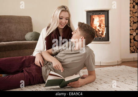 Teenage couple with book lying on carpet Stock Photo