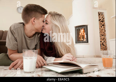 Teenage couple in love cuddling on carpet in front of fireside Stock Photo