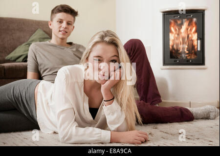 Teenage couple relaxing on carpet in front of fireside Stock Photo