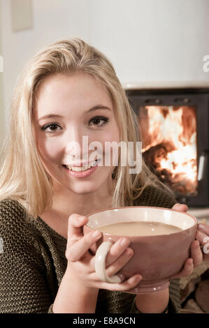 Young pretty blond teenage girl drinking coffee fire Stock Photo