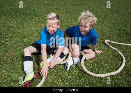 Two young boys resting on grass Tug-of-war Stock Photo