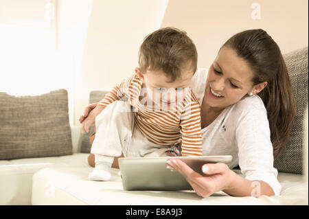 Mother and son using digital tablet in living room, smiling Stock Photo