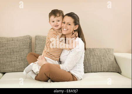 Portrait of mother and son sitting on sofa, smiling Stock Photo