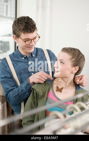 Young man putting necklace around young woman's neck at fashion store Stock Photo