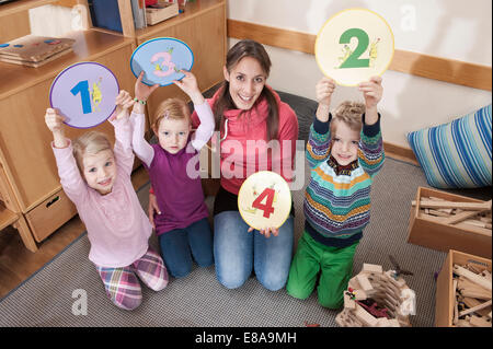 Group picture of female educator and three kids in kindergarten Stock Photo