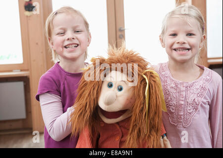 Two little girls, best friends, with doll in kindergarten Stock Photo