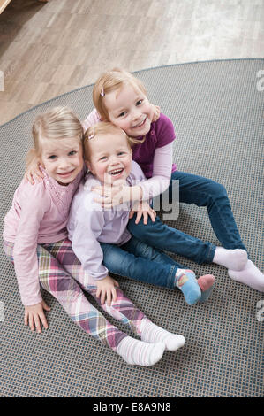 Three little girls, best friends, sitting on ground in kindergarten, elevated view Stock Photo