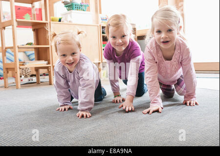 Three little girls, best friends, on all fours in kindergarten Stock Photo