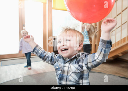 Kids playing with red balloons in kindergarten Stock Photo