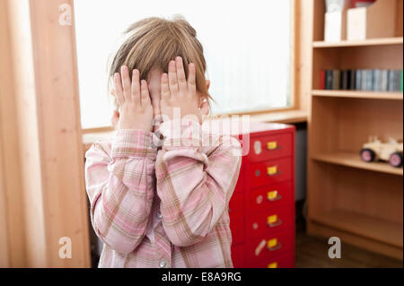 Little girl covering her face with her hands Stock Photo