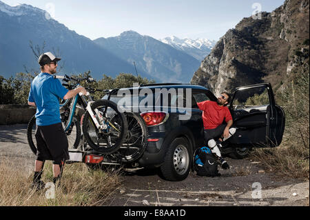 Men taking mountainbikes off car, Italy Stock Photo