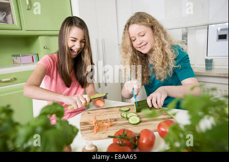 Girls in kitchen chopping vegetables Stock Photo