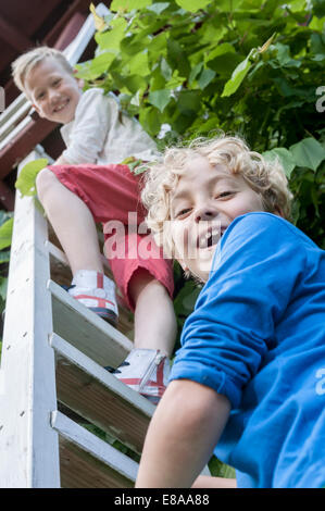 Young boys friends climbing ladder tree-house