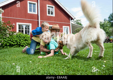 Father and sons pet dog playing on grass