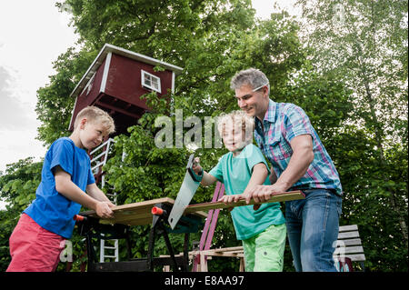 Boy sawing wood building father helping Stock Photo