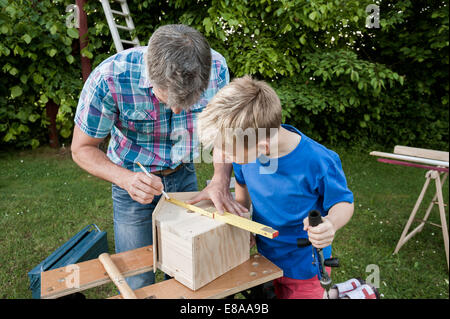 Measuring wood birdhouse building father son Stock Photo