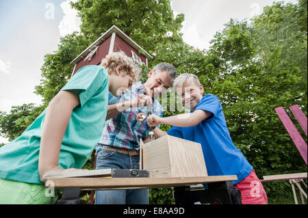 Boys father constructing birdhouse garden wood Stock Photo