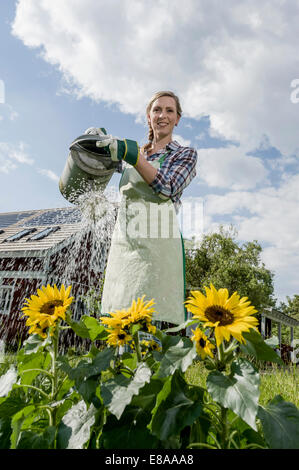 Young woman watering flowers summer Stock Photo